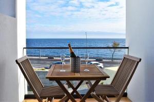 uma mesa com copos de vinho e uma garrafa na varanda em Sky Blue Apartment em Ponta Delgada