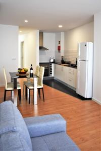 uma cozinha e sala de estar com uma mesa e um frigorífico branco em Sky Blue Apartment em Ponta Delgada