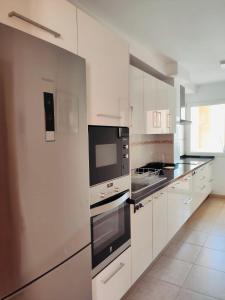 una cocina con armarios blancos y electrodomésticos negros en Vivienda Vacacional Helios - Penthouse Deluxe en Tazacorte