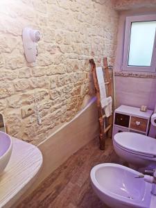 a bathroom with a stone wall and a toilet and a sink at Trully in Alberobello