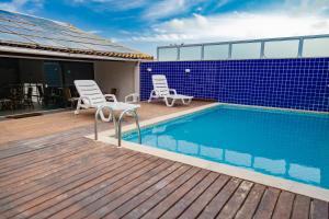 a swimming pool with two chairs and a blue tile wall at Pousada Brisa do Forte in Cabo Frio