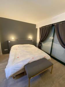 a bedroom with a bed with a bench next to a window at Appartement Golf International de la Baule, Saint Denac, Saint André des Eaux in Saint-André-des-Eaux +21 photos