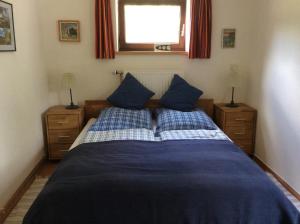 Schlafzimmer mit einem Bett mit blauer Bettwäsche und einem Fenster in der Unterkunft Am Kräutergarten in Kirchlinteln