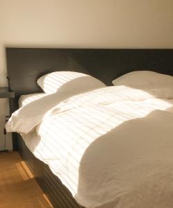 a large white bed with white sheets and pillows at ROOOm Kortrijk in Kortrijk