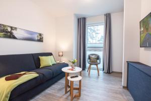 a living room with a blue couch and a table at Appartement "Wolkenschiff" - Oase am Haff in Garz