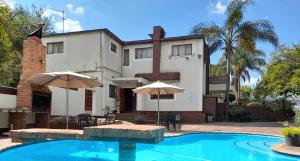 a house with a swimming pool and two umbrellas at Ecotel Midrand in Midrand