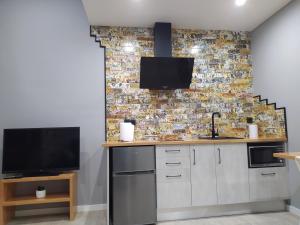 a kitchen with white cabinets and a tv on a brick wall at Paloma blanca in Villalba