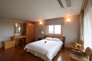 a bedroom with a large white bed and a table at Minitel Soul in Seogwipo