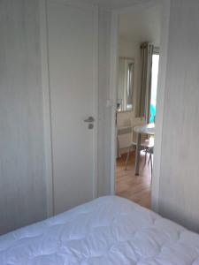a bedroom with a white bed and a dining room at Stacaravan Bredene met tuin nr 2126 in Bredene