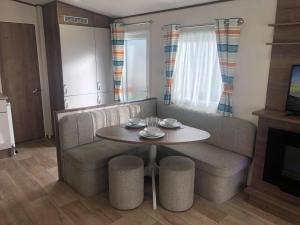 a living room with a table and a couch at Larch Superior Holiday Home in Chapel Saint Leonards