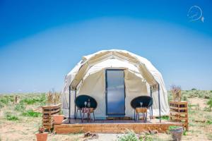 une tente de luxe dans le désert avec 2 chaises devant dans l'établissement Little Amanya Camp, à Amboseli