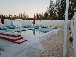 a swimming pool with blue chairs and a white fence at BELL At The Airport Suites - No Smoking & Adults Only - Free Airport Transportation in Nassau