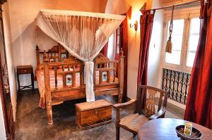 a bedroom with a bed with a canopy and a table at Zanzibar Coffee House in Zanzibar City