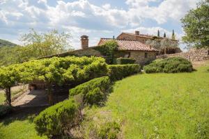an old house in a field with trees and bushes at Le Logge in Pergine Valdarno