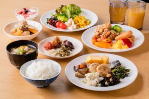 une table avec des assiettes et des bols de nourriture dans l'établissement Hotel Wing International Premium Kyoto Sanjo, à Kyoto