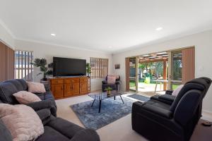 sala de estar con 2 sofás y TV de pantalla plana en Mount Holidaze - Mt Maunganui Holiday Home en Matapihi