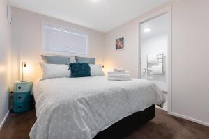 a white bedroom with a large bed with blue pillows at The Little Blue Penguin in Tauranga