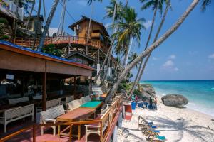 a restaurant on the beach with palm trees and the ocean at Freddies Santai Sumurtiga in Sabang