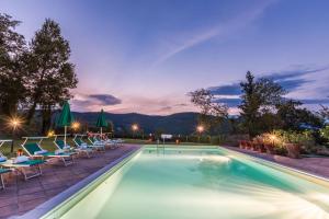 - une piscine de nuit avec des chaises et des tables dans l'établissement Torre Del Cielo, à Monterchi