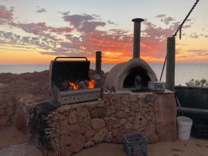 an outdoor oven with a sunset in the background at Wilderness Island in Exmouth