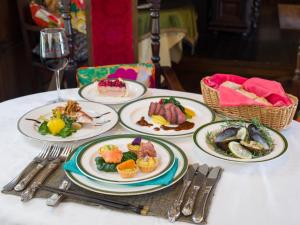 una mesa con platos de comida y una copa de vino en La Mirador, en Kamogawa