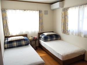 Duas camas num pequeno quarto com uma janela em Izu Shirada Villa 伊豆白田家 em Higashiizu