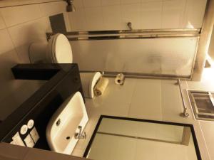 a bathroom with a white toilet and a sink at Silver Oaks Suites & Hotel in Manila