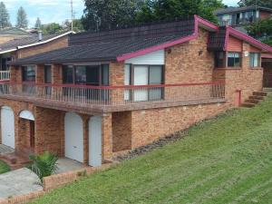 a brick house with a balcony on a hill at Cloud Nine Gerringong in Gerringong