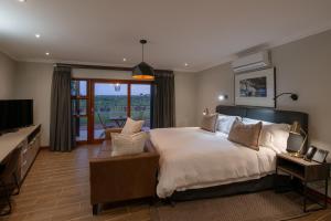 um quarto com uma cama grande e uma televisão em Buckler's Africa Lodge Kruger Park em Komatipoort