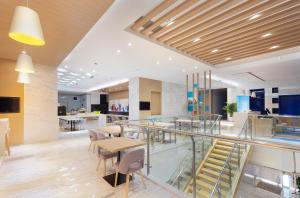 a lobby with a staircase and tables and chairs at Holiday Inn Express - Qingdao West Coast, an IHG Hotel in Huangdao