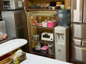 a kitchen with a refrigerator and a microwave at Ishigakijima Guesthouse Seacoro in Ishigaki Island