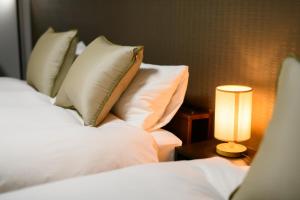 a bedroom with two beds with pillows and a lamp at JP INN Kyotoeki Kita Gakurincho in Kyoto