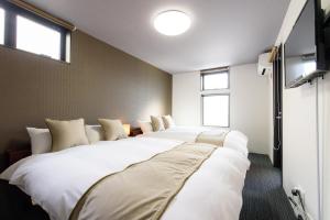 a room with three large white beds with windows at JP INN Kyotoeki Kita Gakurincho in Kyoto