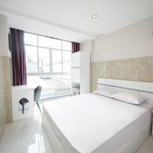 een witte slaapkamer met een groot bed en een raam bij SaiGon CoZy Hotel "241 Pham Ngu Lao Street'' in Ho Chi Minh-stad