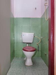 a toilet with a red seat in a green tiled bathroom at SPOT ON 90144 Corridor Hotel 1 in Pekan