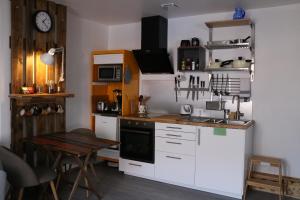 eine Küche mit weißen Schränken, einem Tisch und einer Uhr in der Unterkunft Le Studio de Sophie in Vendôme