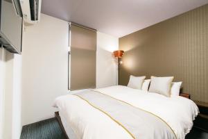 1 dormitorio con 1 cama grande con sábanas blancas en JP INN Kyotoeki Kita Gakurincho en Kioto