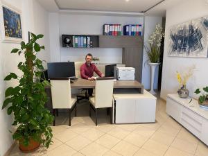 a man sitting at a table with a computer at Residence Perla in Rimini