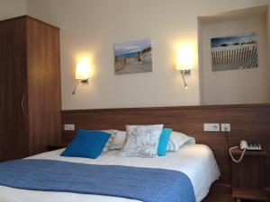 1 dormitorio con 2 camas y almohadas azules y blancas en Cit'Hotel Du Port Rhu, en Douarnenez