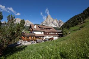 a house on a hill with a mountain in the background at Berghotel Ladinia in Corvara in Badia
