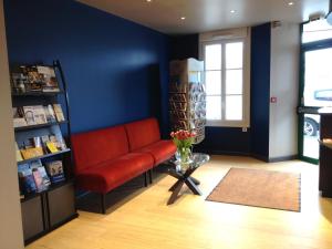 Habitación con sofá rojo y estante para libros. en Cit'Hotel Du Port Rhu, en Douarnenez