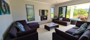 a living room with two couches and a fireplace at Augusta Grand Pauanui, a Golfers Dream House in Pauanui