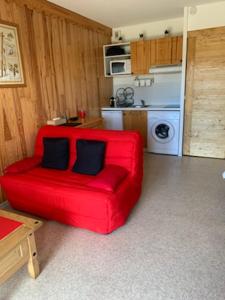 un sofá rojo con 2 almohadas en la cocina en Grand studio 5 personnes Station Familiale Montclar, en Montclar