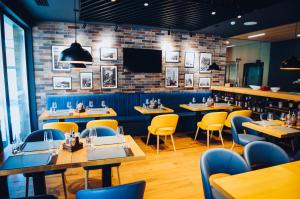 a restaurant with tables and chairs and a tv at Hugo Hotel in Satu Mare