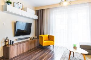 salon z telewizorem i żółtym krzesłem w obiekcie Bulwar Apartament w Głogowie