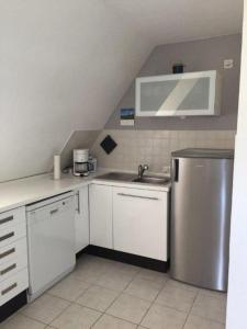 eine Küche mit weißen Schränken und einem Kühlschrank aus Edelstahl in der Unterkunft Wattläufer in Tating