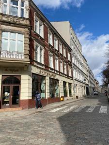 een persoon die door een straat loopt voor gebouwen bij Art Apartment Szczecin II in Szczecin
