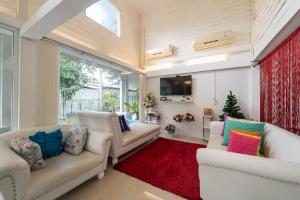 uma sala de estar com dois sofás brancos e um tapete vermelho em Banlomnow em Chiang Rai
