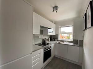 a white kitchen with white cabinets and a sink at Saffron Court by Wycombe Apartments - Apt 12 in High Wycombe