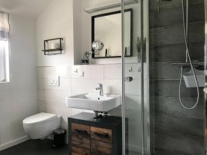 a bathroom with a sink and a toilet and a shower at Feriendorf Rugana - Komfortplus Appartement mit 1 Schlafzimmer A03 in Dranske +5 photos